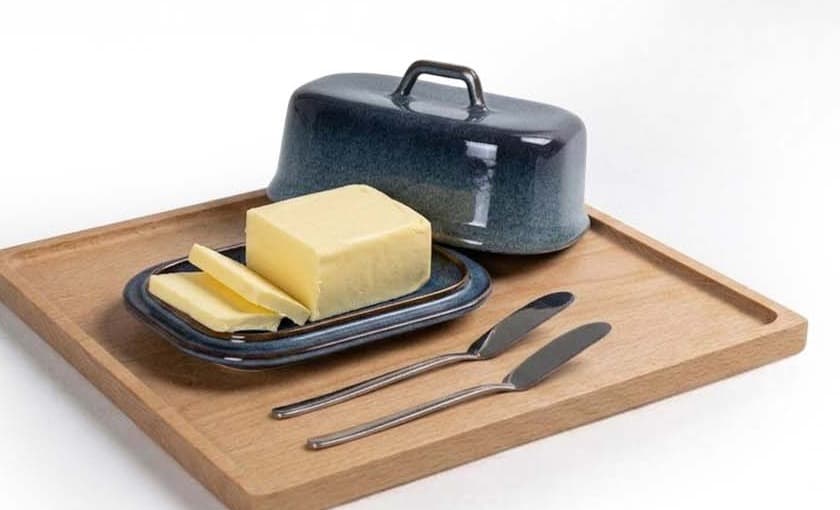 Blaue Butterdose geöffnet mit Butter auf einem Holzbrett